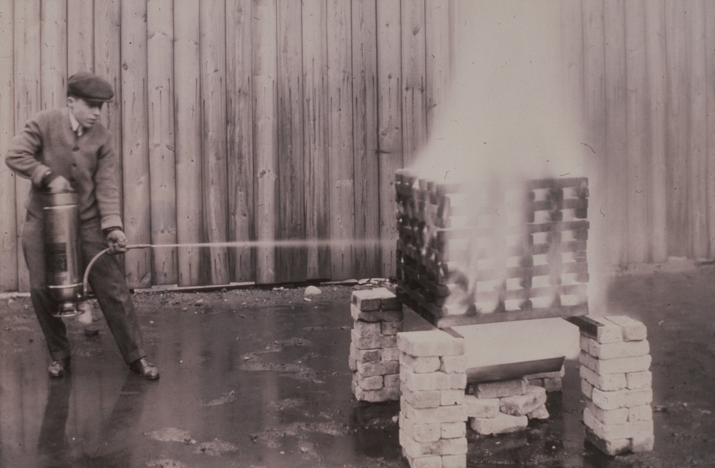 A UL engineer tests a fire extinguisher, ca. 1910.