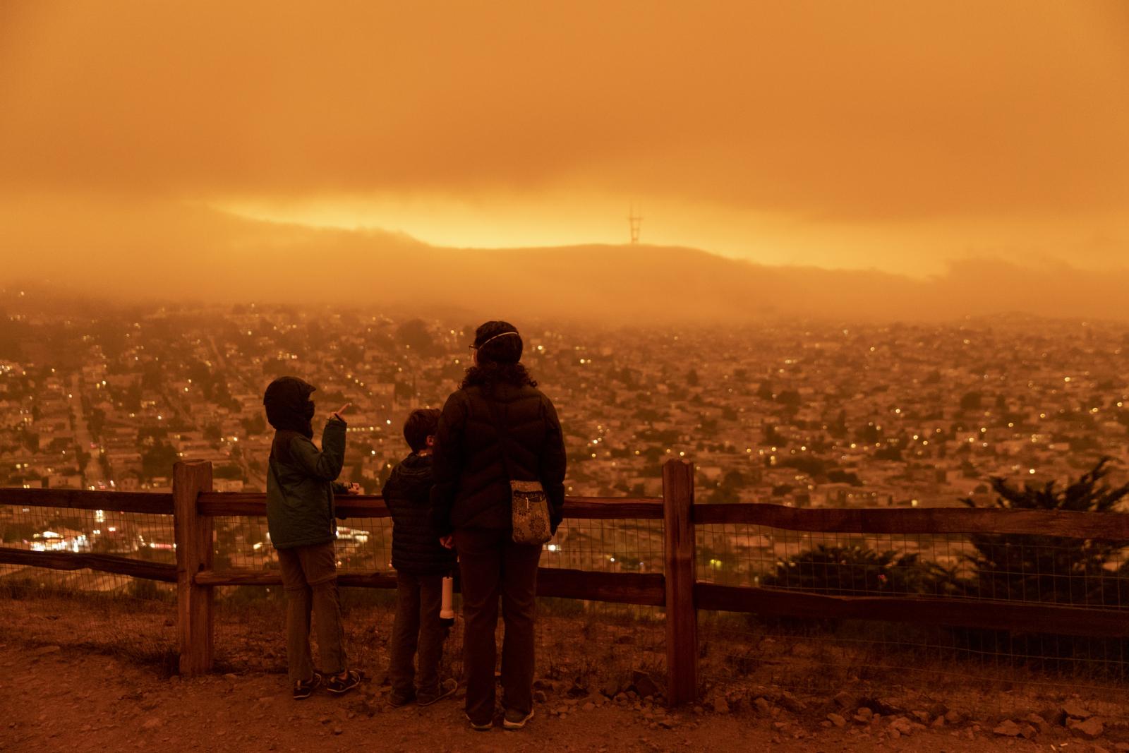 Adult and kids standing in orange smog wearing face masks