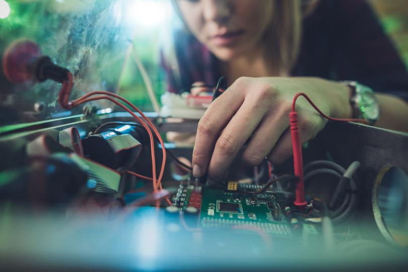 Close up of a woman repairing electrical component of a computer. - stock photo