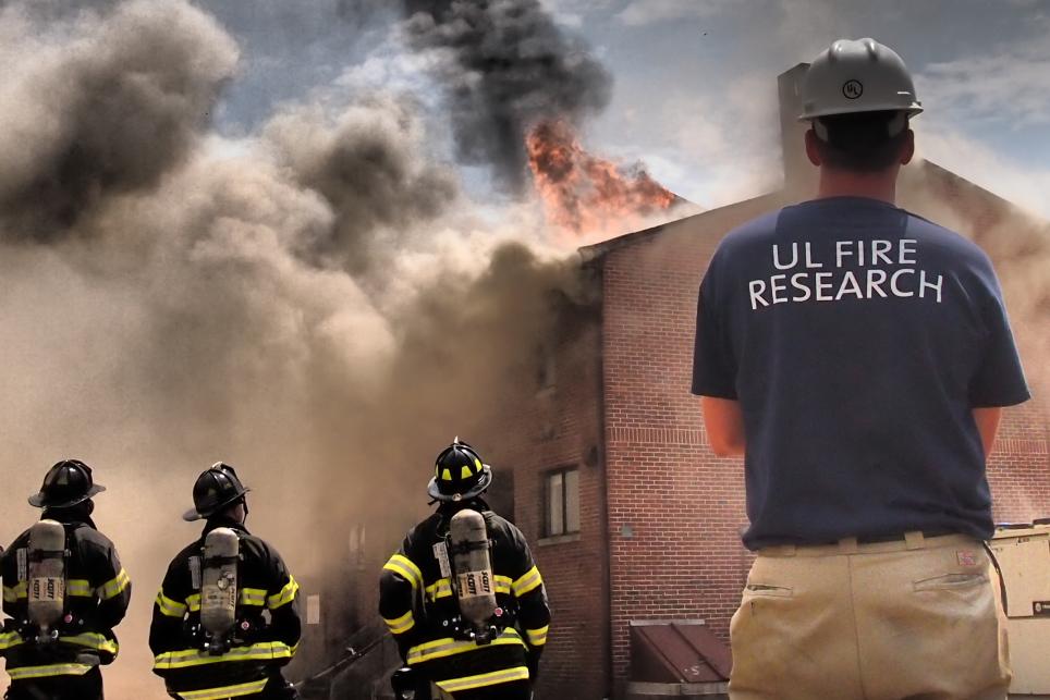 firefighters and UL researchers standing in front of a building on fire 