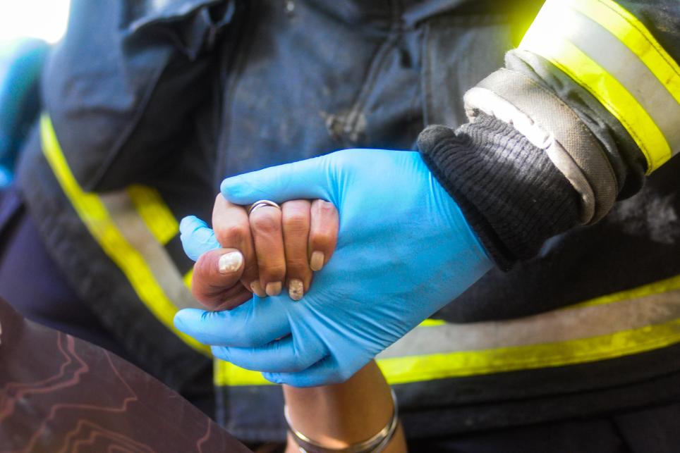 A firefighter holds a woman's hand
