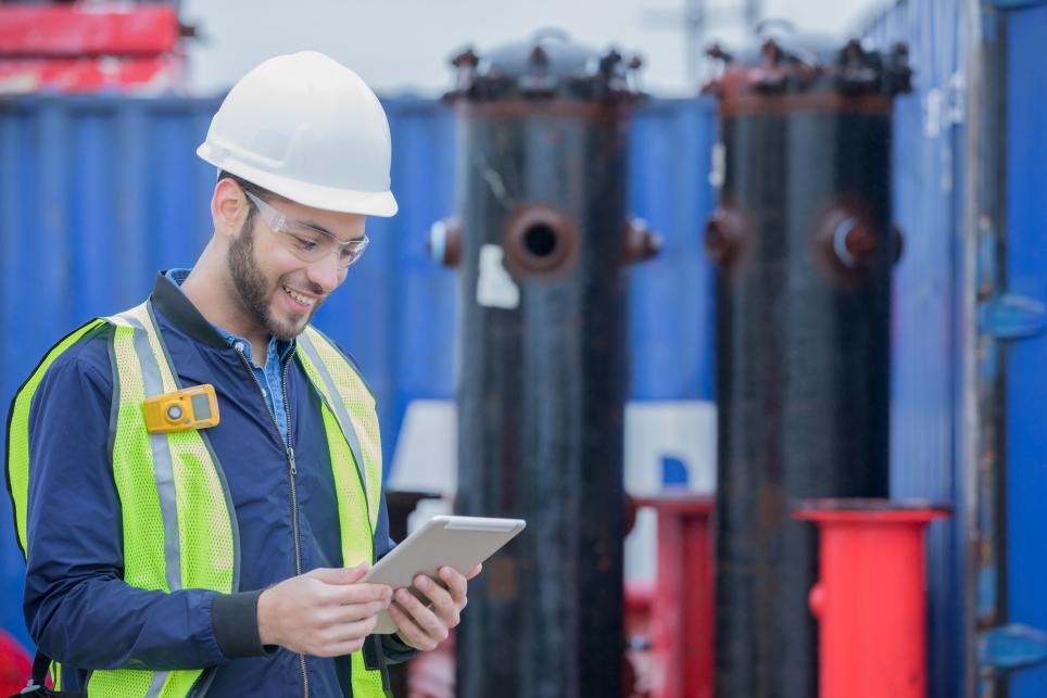 Pipeline engineer using digital tablet while working at oil and gas job site