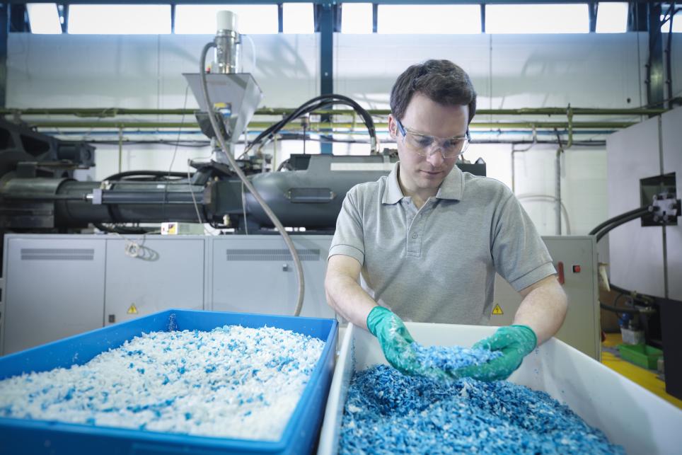 Man inspecting recycled polymers in a manufacturing facility