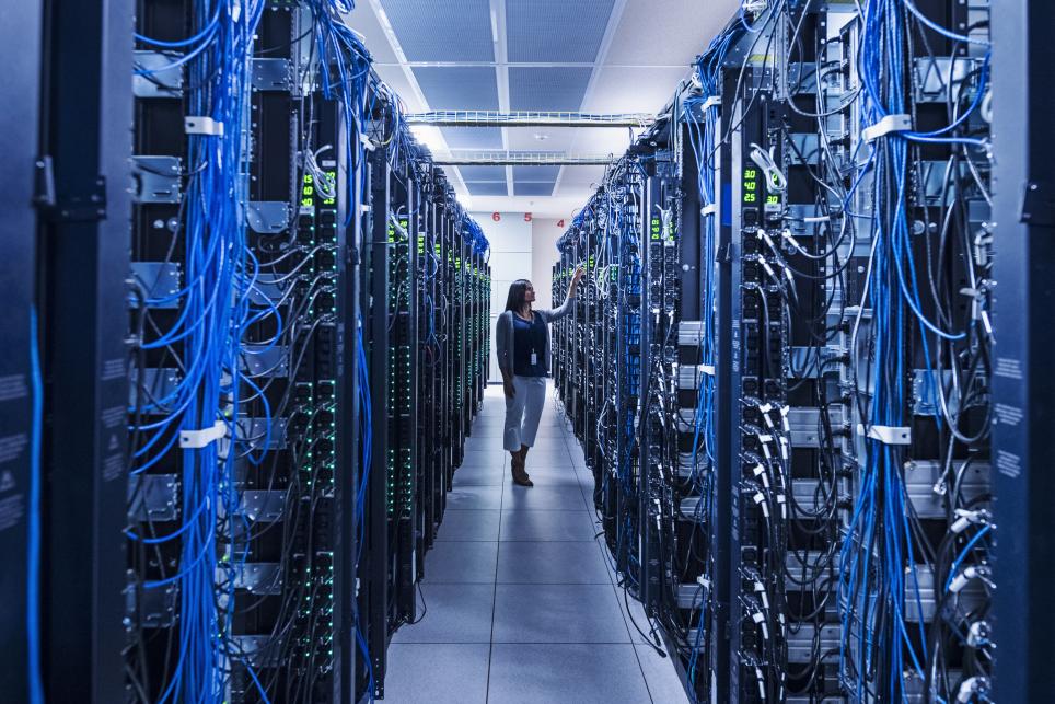 person walking through computer servers in a data center