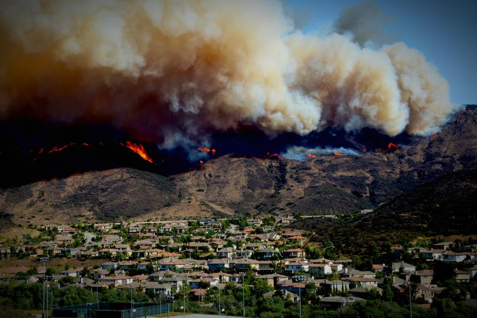 wildfire on top of mountain with homes in the valley