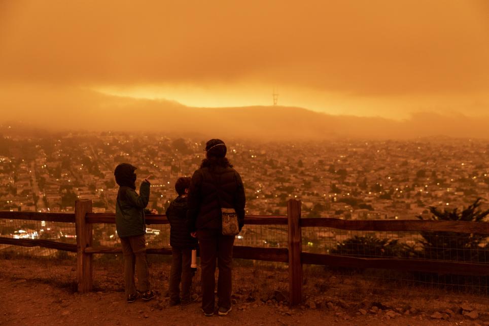 Adult and child standing in orange smog wearing face masks