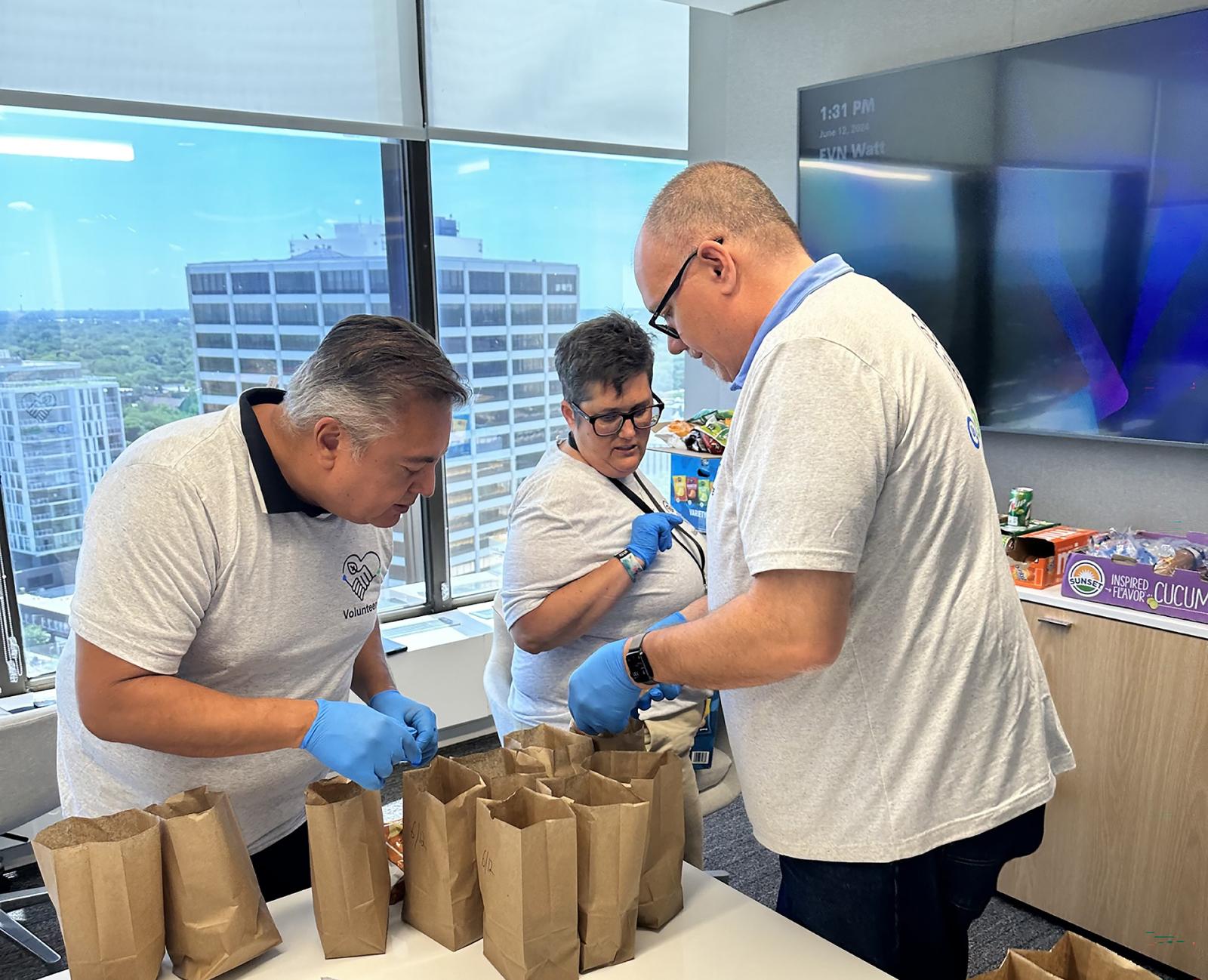 IT team members Rick Gutierrez, at left, Karen Smilie, and Ron Tomlinson do a final check on a batch of sack lunches their team made for Connections locations.