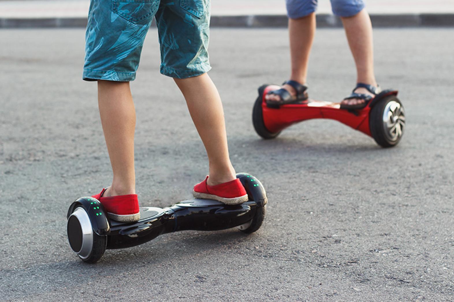 Young boys stands on the black gyro scooter outdoors, soft focus background