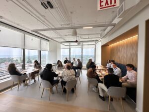 a group of people sitting around tables in a room with windows