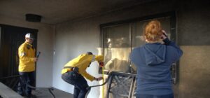 two men and one woman inspecting and photographing a fire damaged window