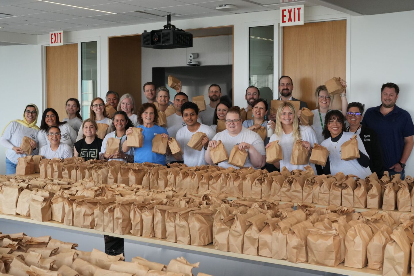 A group of UL Research Institutes employees standing behind 1,000 lunches which were packaged by the team for Connections for the Homeless