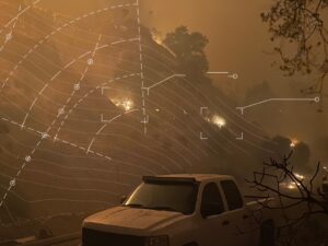 Wildfire spreading across a hillside at night with white contour lines and markers overlaid on top representing wildfire risk modeling.